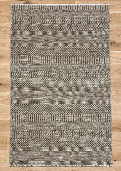 A rectangular woven area rug with a textured horizontal striped pattern in gray and beige tones, laid flat on a light wood floor.